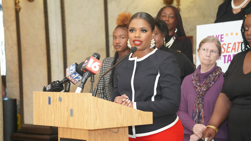 Professional woman at podium with supporters behind her